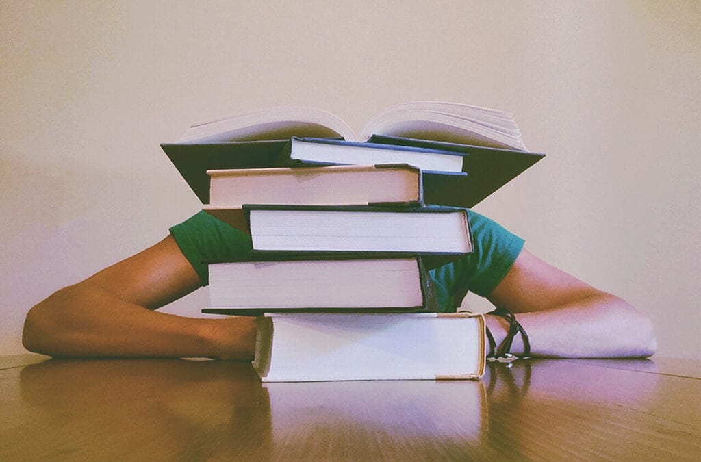 Person hiding behind a stack of books