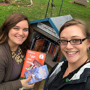 Two women standing near mailbox full of books