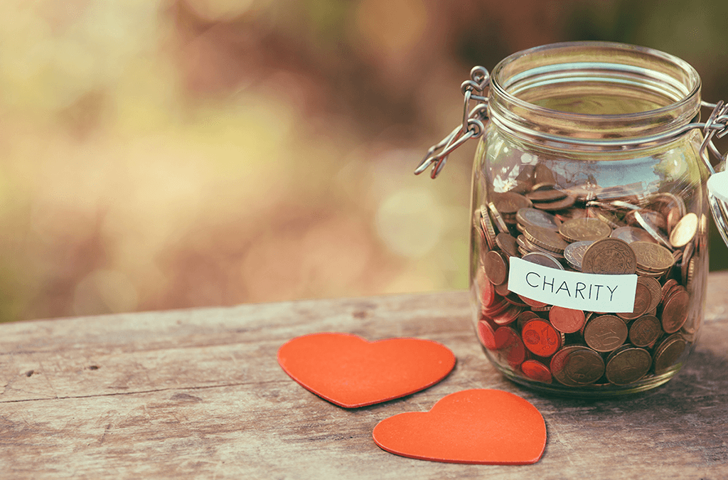 Jar full of money for charity and paper hearts on picnic table outside
