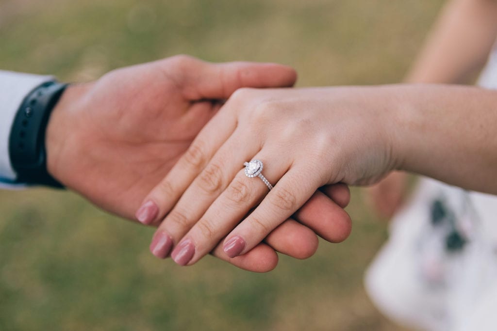 Man holding woman&#039;s hand showing off new engagement ring